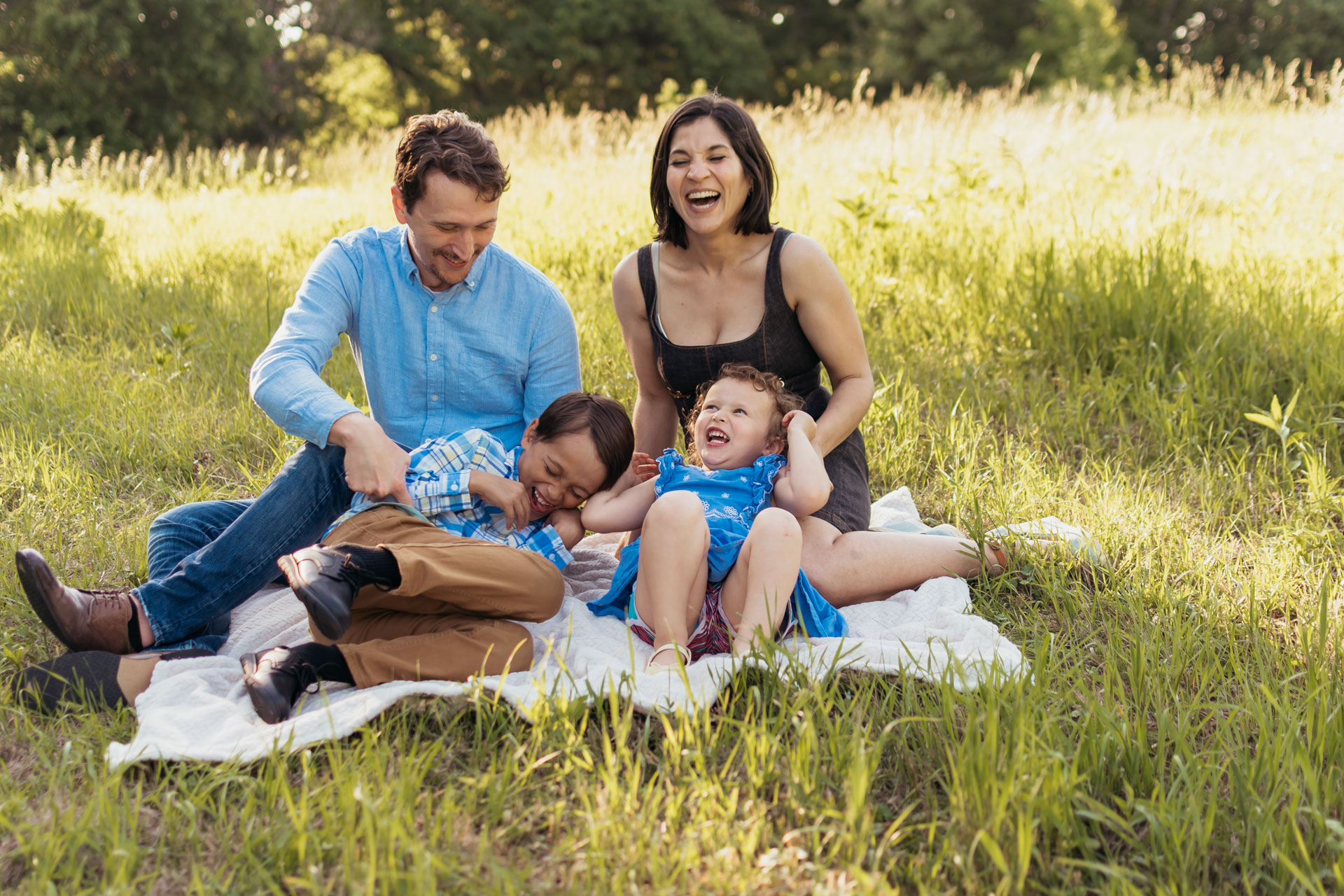 Parents and children laughing together during a golden-hour family photo session in a Pittsburgh park