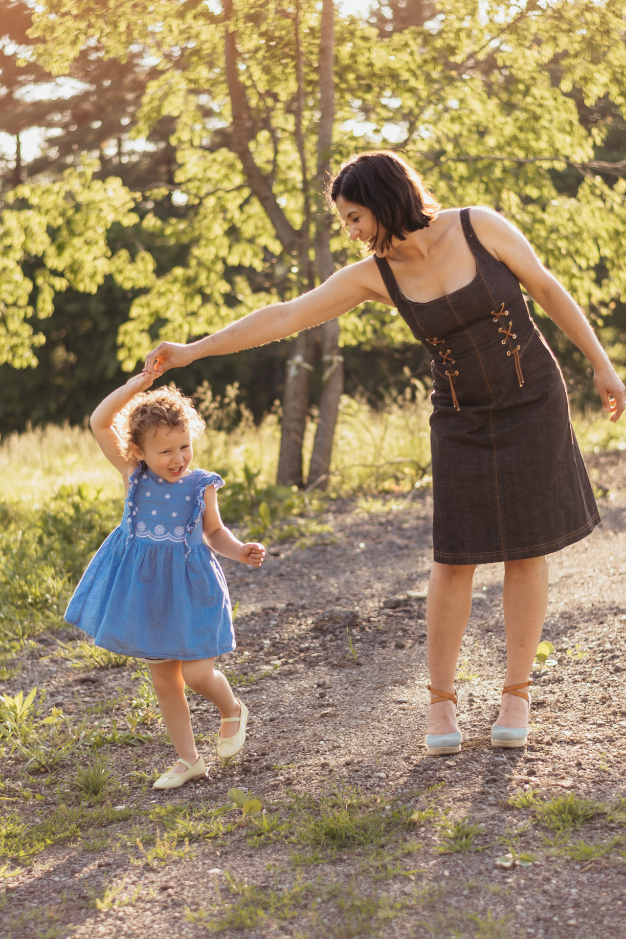 Mother spinning her toddler daughter on a sunlit path during a family session in the South Hills
